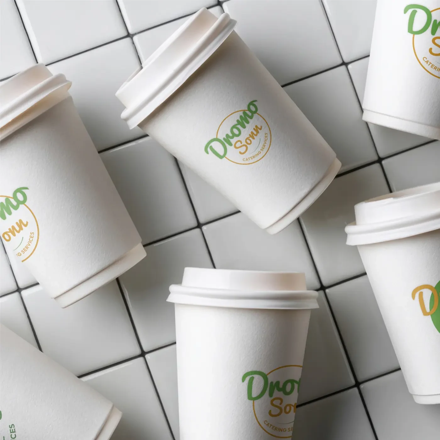 Dromo Sonn branded to-go coffee cups on white tile